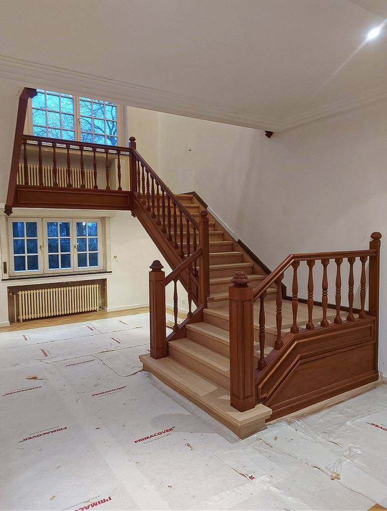 Classic wooden staircase with white balusters after renovation
